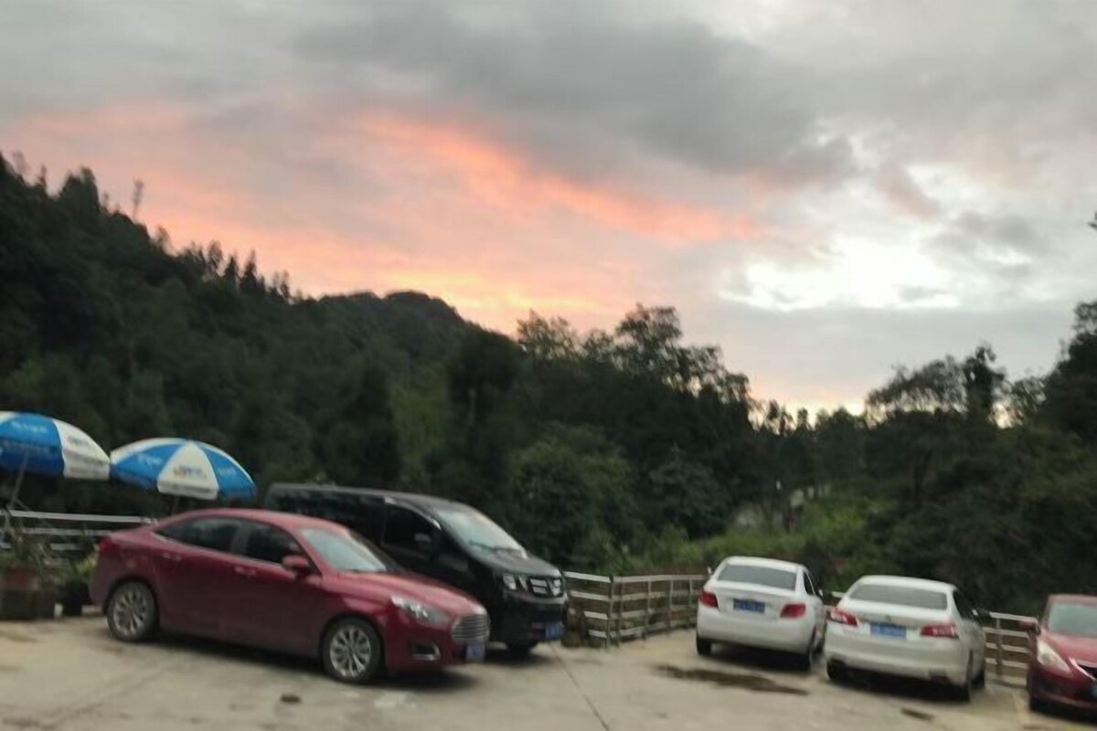 A parking lot with several cars and a few umbrellas.