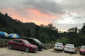 A parking lot with several cars and a few umbrellas. - Mount Emei Feng Lin Yue Hotel (Emeishan City)