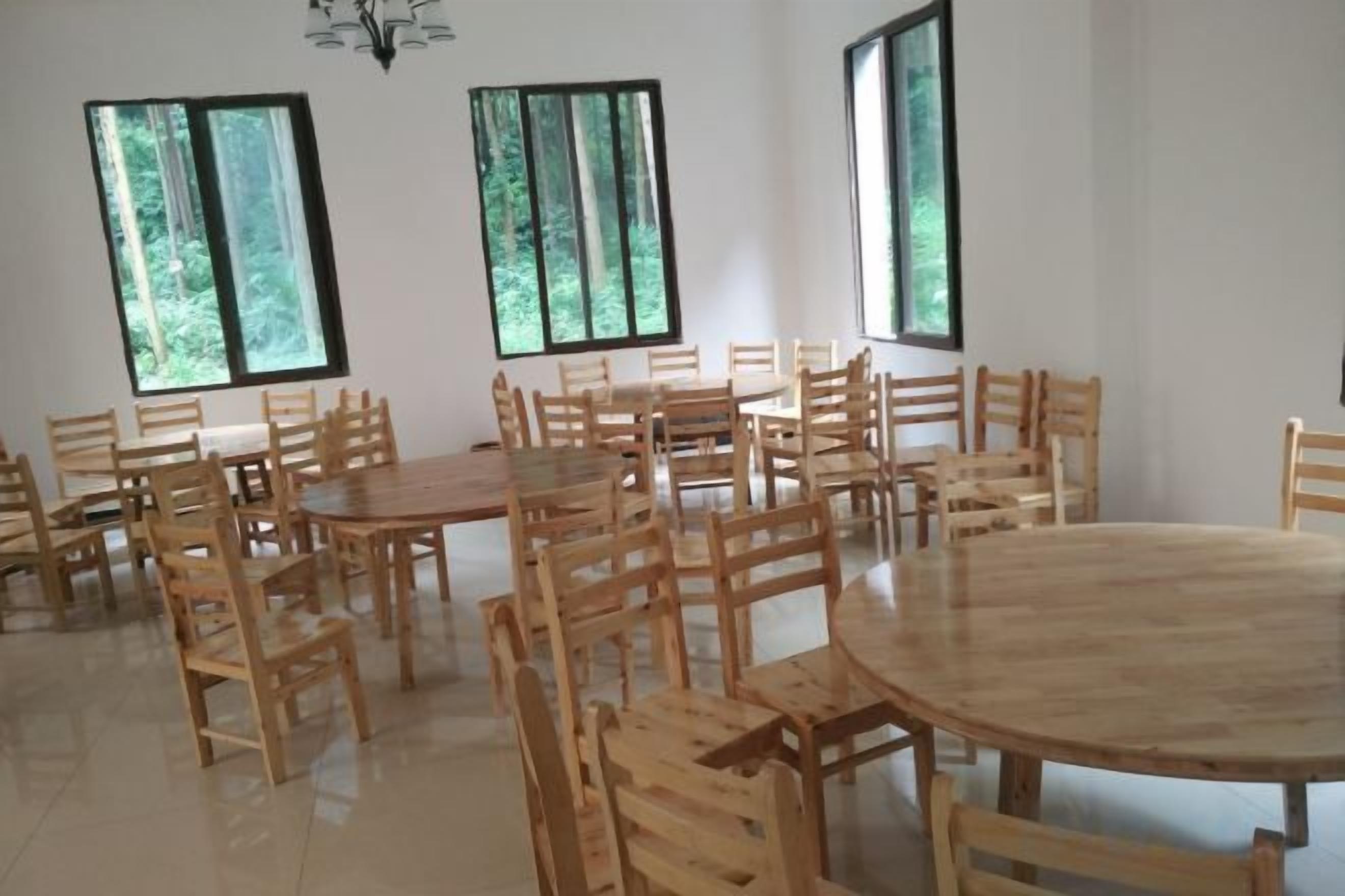 A conference room with multiple tables and chairs, large windows, and a chandelier.