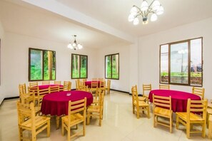 A conference room with round tables, chairs, and large windows with a view. - Mount Emei Feng Lin Yue Hotel (Emeishan City)