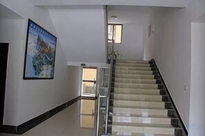 A staircase with a handrail, a poster on the wall, and a door at the top. - Mount Emei Feng Lin Yue Hotel (Emeishan City)