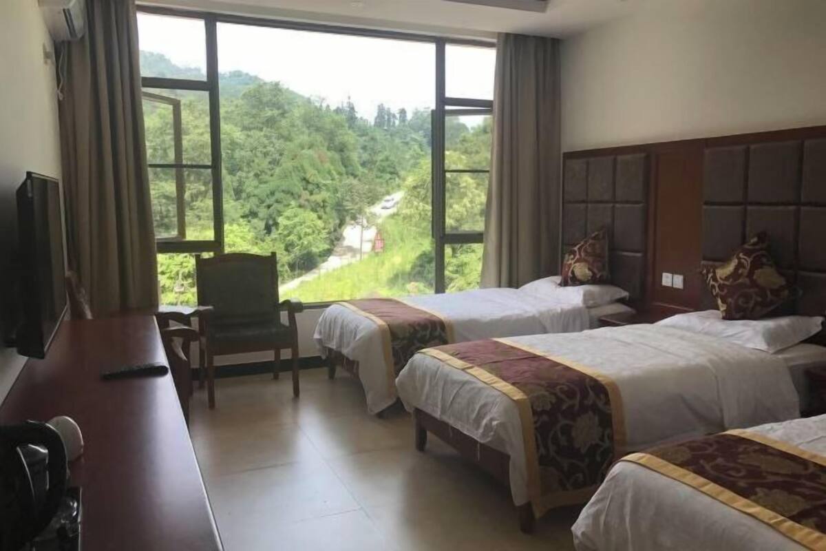 A hotel room with two beds, a desk, a chair, and a TV.