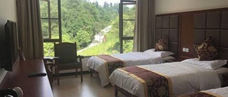 A hotel room with two beds, a desk, a chair, and a TV.