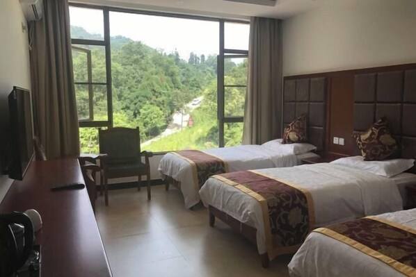 A hotel room with two beds, a desk, a chair, and a TV. - Mount Emei Feng Lin Yue Hotel (Emeishan City)