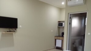 Ein Hotelzimmer mit einem Bett, einem flachbildfernseher an der Wand, einer Mikrowelle und einer Tür.