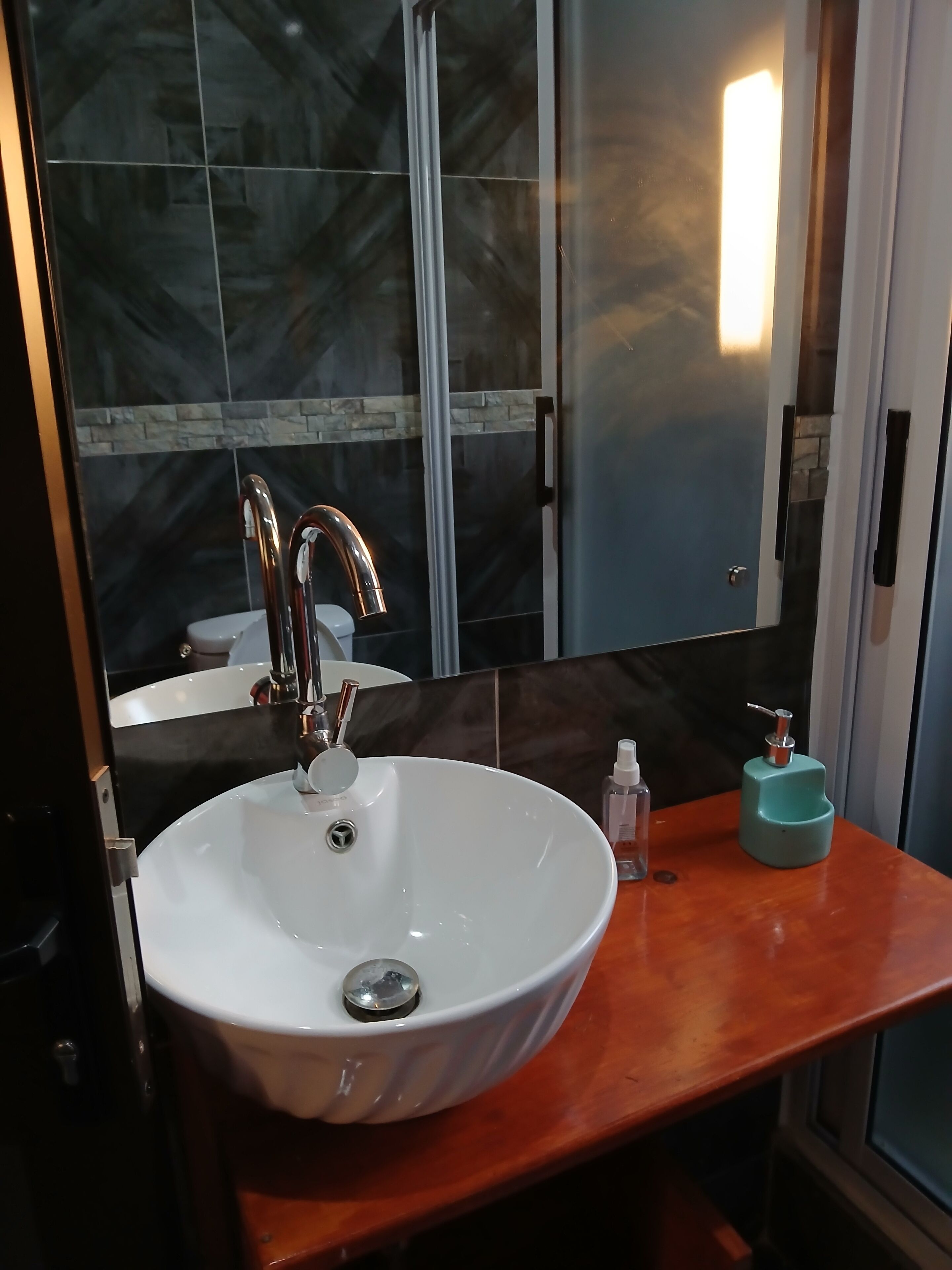 A bathroom with a white vessel sink, a mirror, and a wooden vanity.