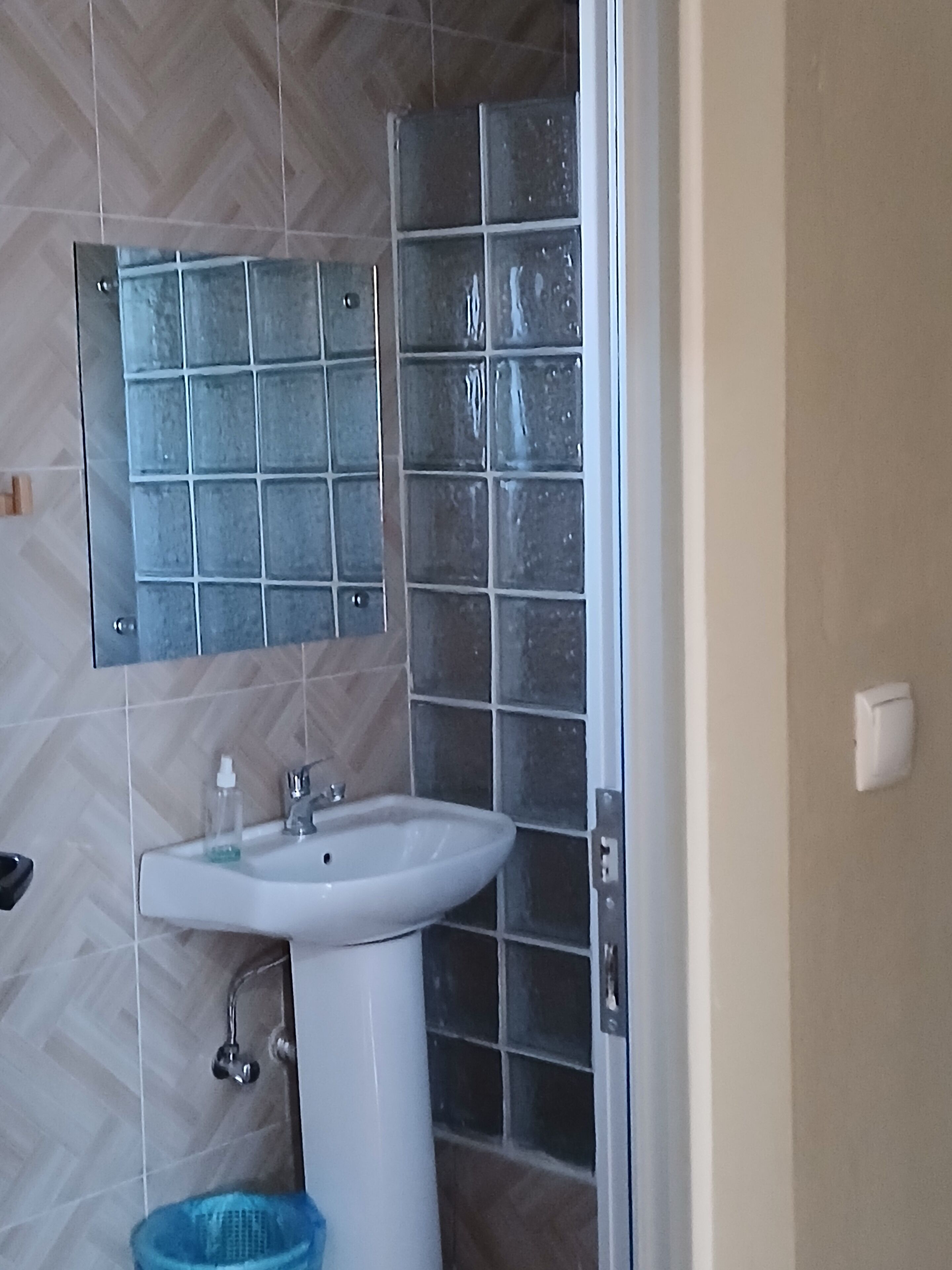 A bathroom with a white sink, a mirror, and tiled walls.