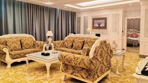 Habitación de hotel con sofá, una mesita, una lámpara y cama con cabecera.