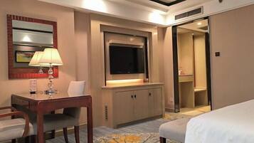Een hotelkamer met een bed, een bureau met lamp, een televisie en een kledingkast.