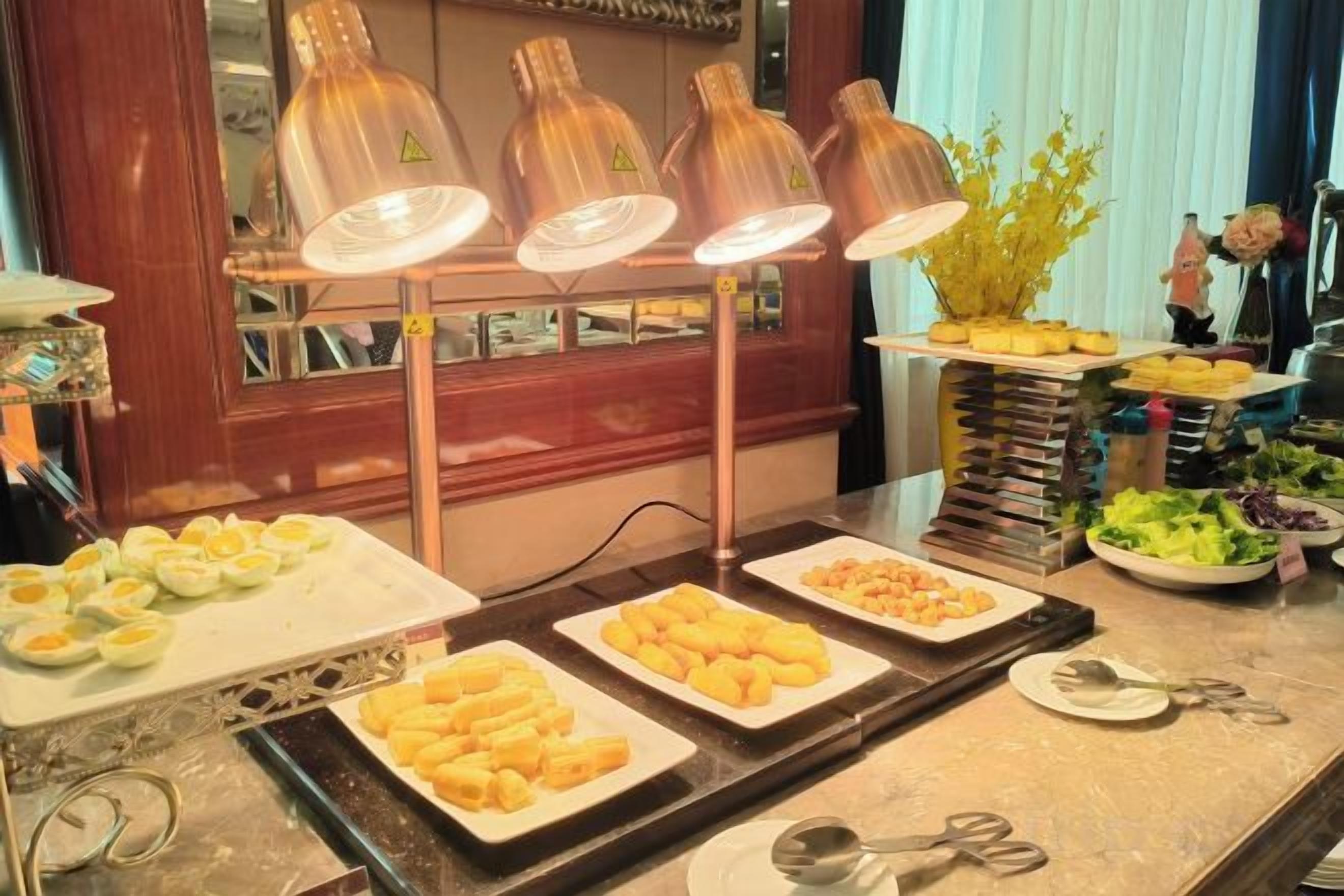 A buffet with various food items and a decorative plant arrangement.