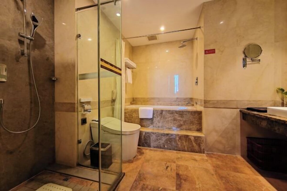 A modern bathroom with a glass-enclosed shower, a toilet, a bathtub, and a vanity with a mirror.