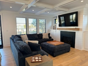 A living room with a sectional sofa, a wooden coffee table, and a fireplace. - OCEAN BLOCK - BRAND NEW HOME W HEATED POOL AND ELEVATOR (Surf City)