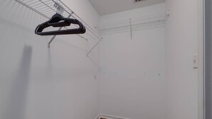 Une pièce avec un plancher en bois, des murs blancs et un ventilateur de plafond.