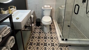 Un baño con lavamanos, inodoro y zona de ducha blanca.