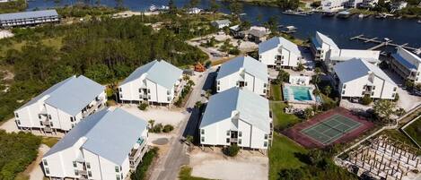 A coastal residential area with modern white buildings, a tennis court, and a swimming pool.
