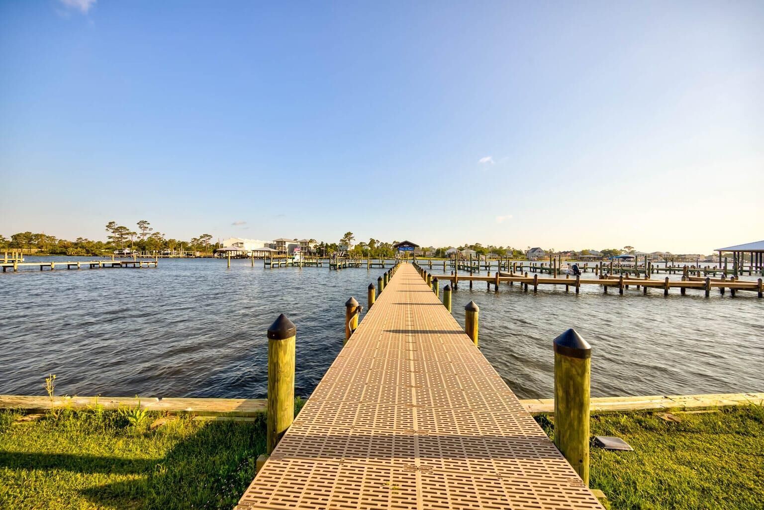 A pier extending into calm water, with a clear sky above.