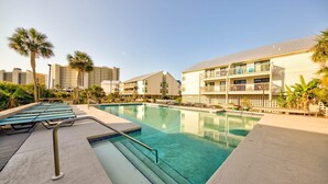A swimming pool with lounge chairs, a poolside deck, and a building with balconies. - Cotton Bayou 7H (Orange Beach)
