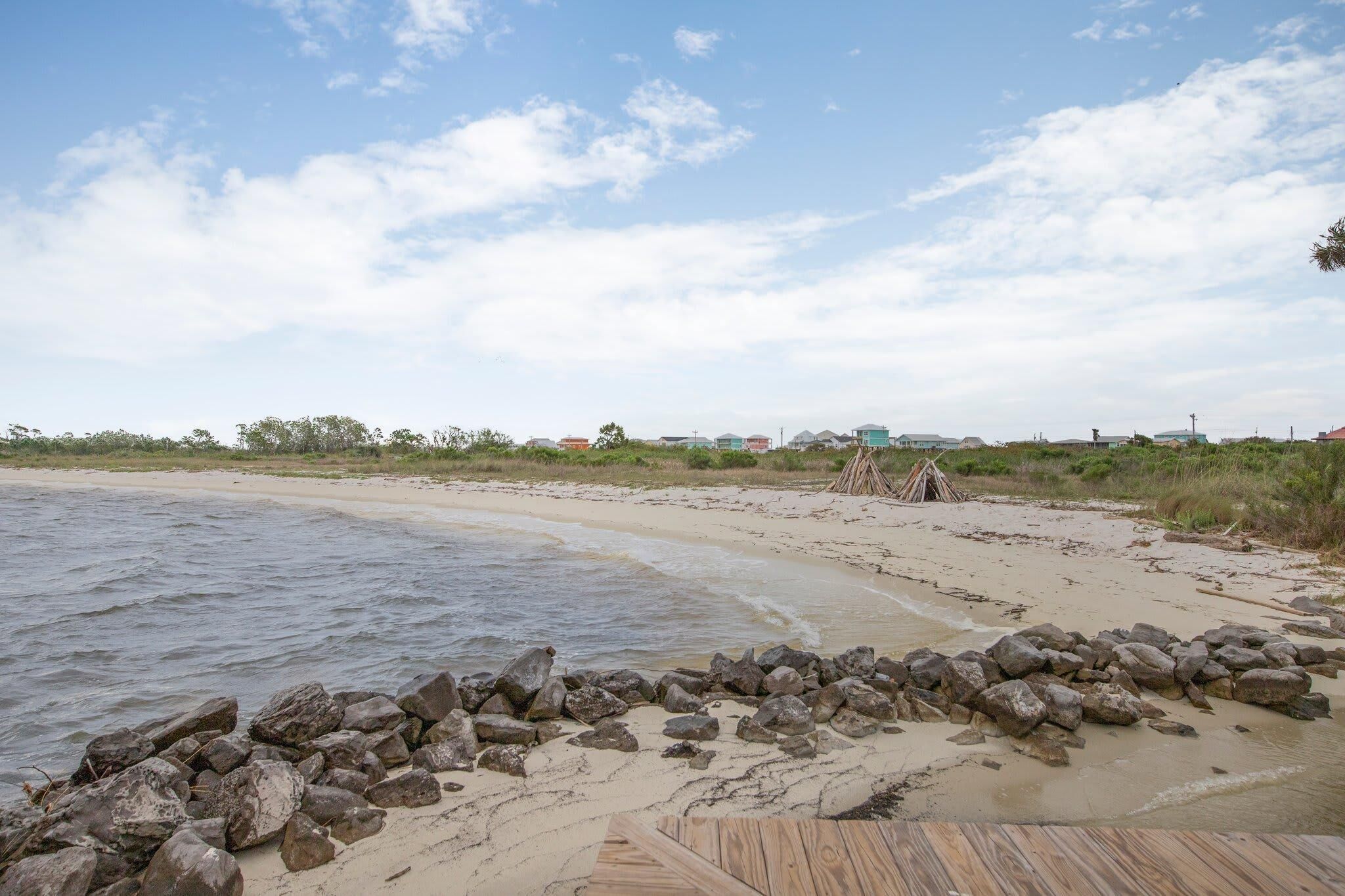 A beach with a wooden deck and a rocky shoreline.