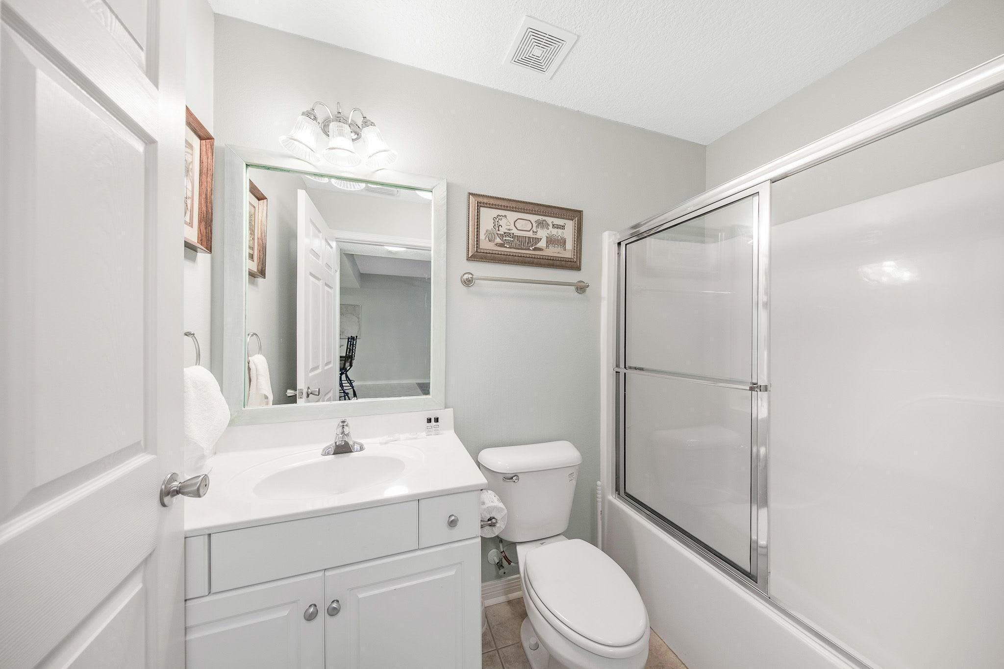 A bathroom with a white sink, toilet, and a glass shower enclosure.