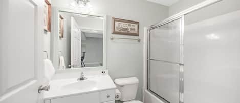 A bathroom with a white sink, toilet, and a glass shower enclosure.