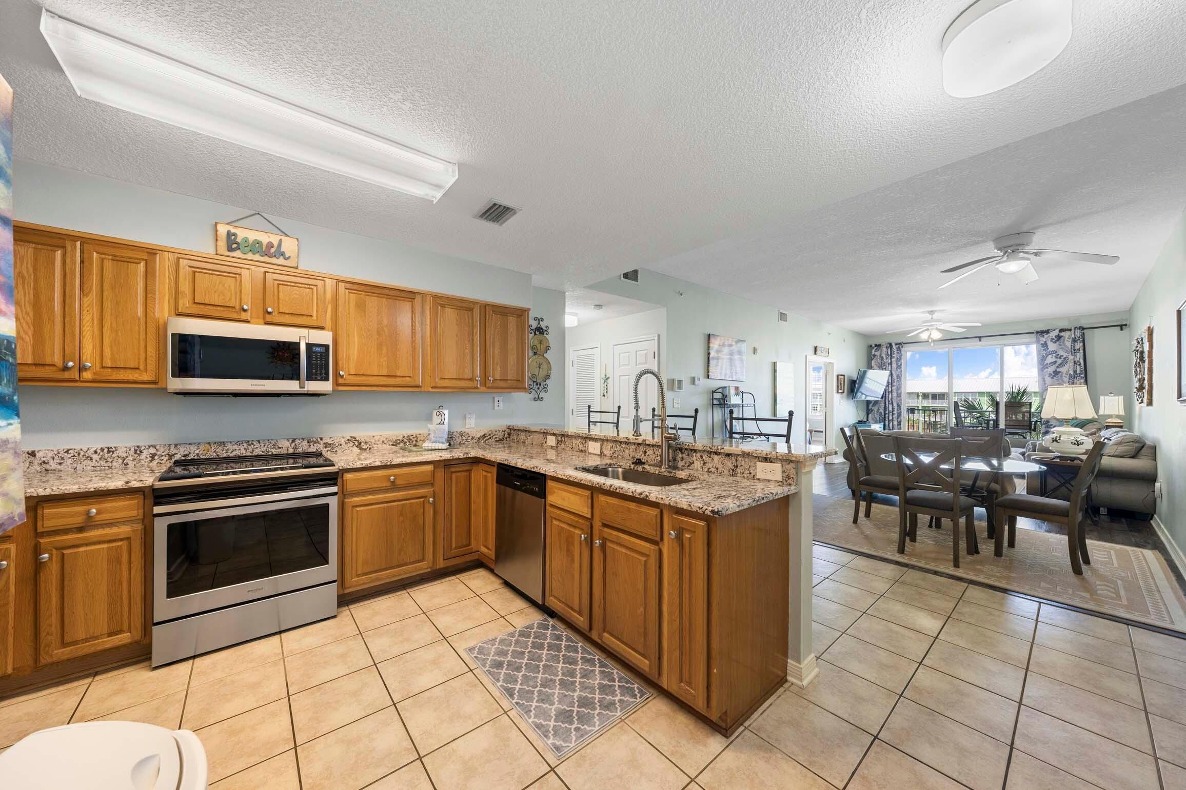 A kitchen with wooden cabinets, stainless steel appliances, a granite countertop, and a dining area with a table and chairs.
