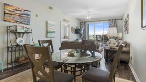 A dining area with a glass table, chairs, and a view of the outdoors.