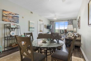 Un comedor con una mesa de vidrio, sillas y vistas al exterior.
