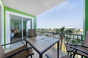 A balcony with a table and chairs, a sliding glass door leading to a room, and a view of the cityscape.