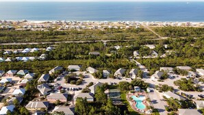 A resort with multiple bungalow-style buildings, a central swimming pool, and a beach view. - The Rookery 2202 (Gulf Shores)