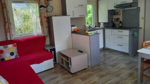 A compact living space with a kitchenette, a sofa, and a dining area. - Mobile home rental (Agde)