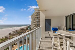 Un balcon avec vue sur une plage et une piscine.