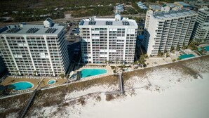 A high-rise hotel with multiple balconies, a beachside pool, and a beach access walkway. - Pelican Pointe 1505 (Orange Beach)