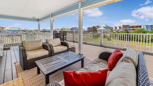 A covered outdoor area with a sofa, chairs, and a table. - Sandy Feet Retreat (Gulf Shores)