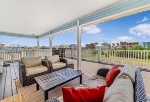 A covered outdoor area with a sofa, chairs, and a table. - Sandy Feet Retreat (Gulf Shores)