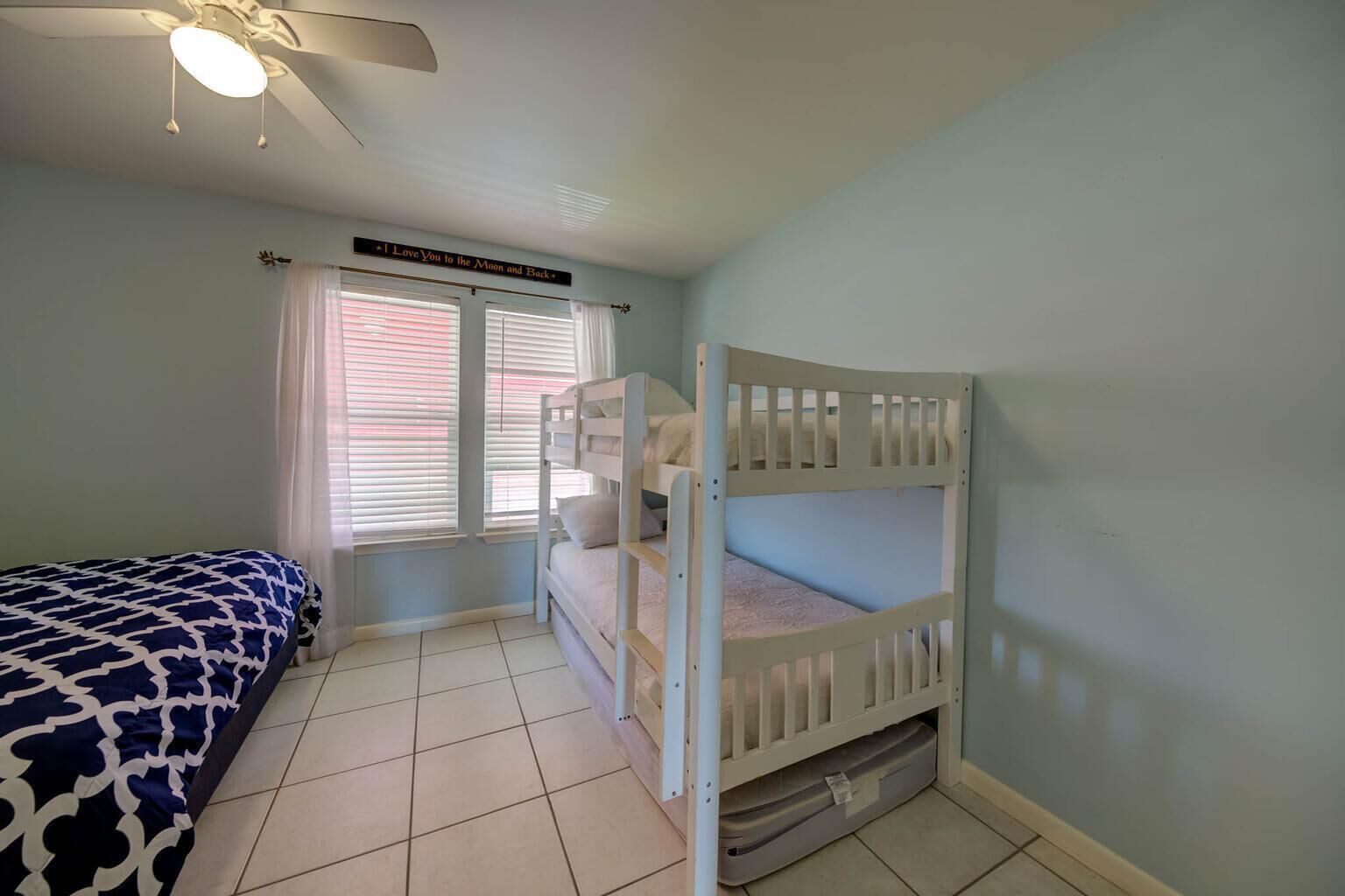 A bedroom with a bunk bed, a single bed, a ceiling fan, and a window with blinds.