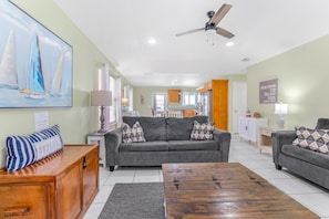 A living room with a sofa, coffee table, and a painting of sailboats.