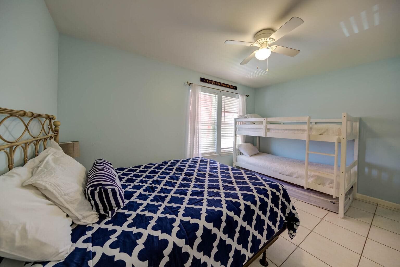 A bedroom with a bed, a bunk bed, a ceiling fan, and a window with blinds.