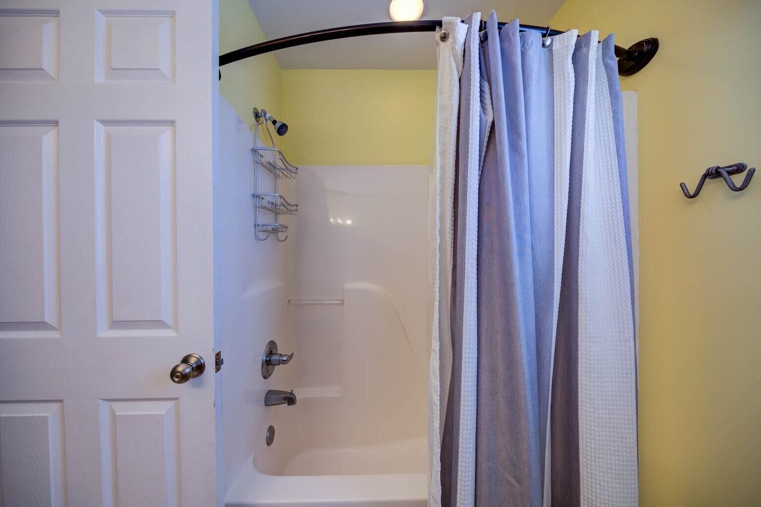 Ein Badezimmer mit einer weißen Badewanne, einer Duschvorhang und einem Handtuchhalter.