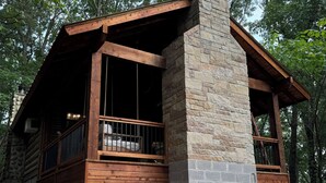 Eine Blockhütte mit einem Steinkamin, einer Holzdiele und großen Fenstern.