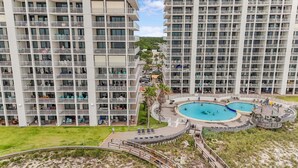 A high-rise hotel with multiple balconies, a central swimming pool, and a surrounding deck area. - Summer House 1405a (Orange Beach)