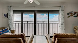 A room with a large window, a ceiling fan, and a view of the sky. - Gulf Tower 3C (Gulf Shores)