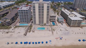 A high-rise hotel with multiple balconies, a central swimming pool, and a beach area with sun loungers. - Gulf Tower 3C (Gulf Shores)