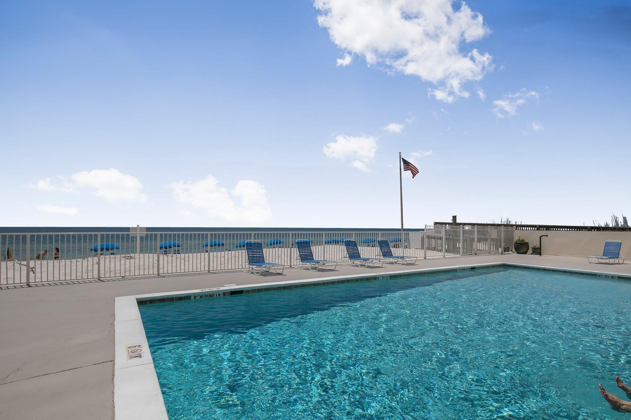 A swimming pool with lounge chairs and a flagpole.