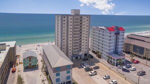 A high-rise hotel with multiple floors, a parking lot, and a beach view. - Gulf Tower 3C (Gulf Shores)