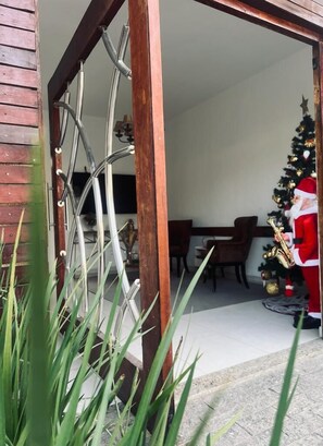 Een houten deurkozijn leidt naar een ruimte met een eethoek en een kerstboom.