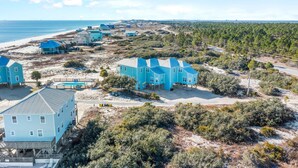 A coastal residential area with multiple houses, some with blue roofs, and a beach in the background. - Lotsa Sand C (Gulf Shores)