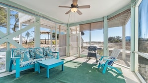 A covered outdoor area with a blue sofa, a table, and a chair. - Lotsa Sand C (Gulf Shores)