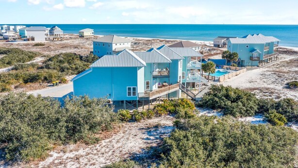 A coastal property with multiple buildings, including a large blue structure with a pool and a smaller adjacent building. - Lotsa Sand C (Gulf Shores)