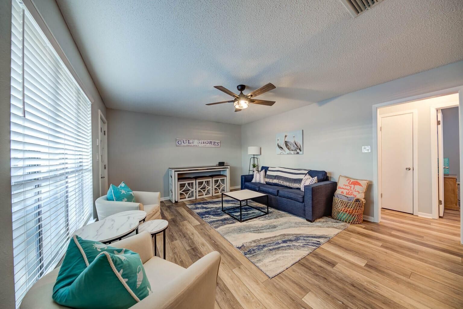 A living room with a ceiling fan, a sofa, a coffee table, and a rug.