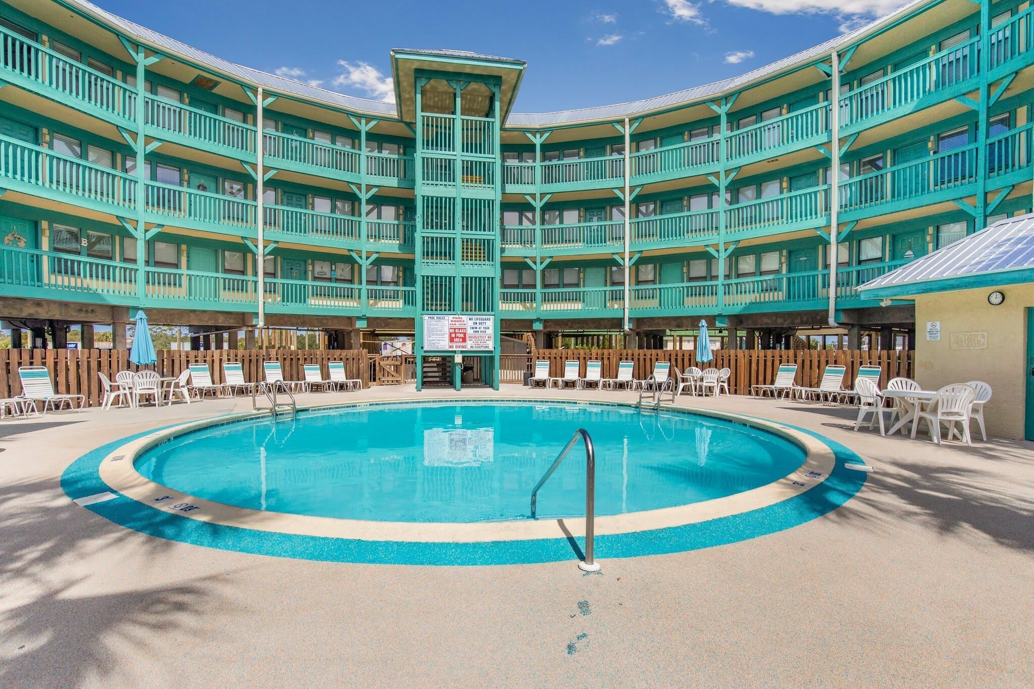 A large indoor swimming pool surrounded by multiple balconies with a wooden fence.